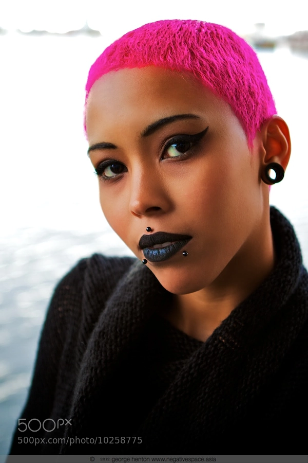 mulher negra com piercing medusa e cabelo rosa