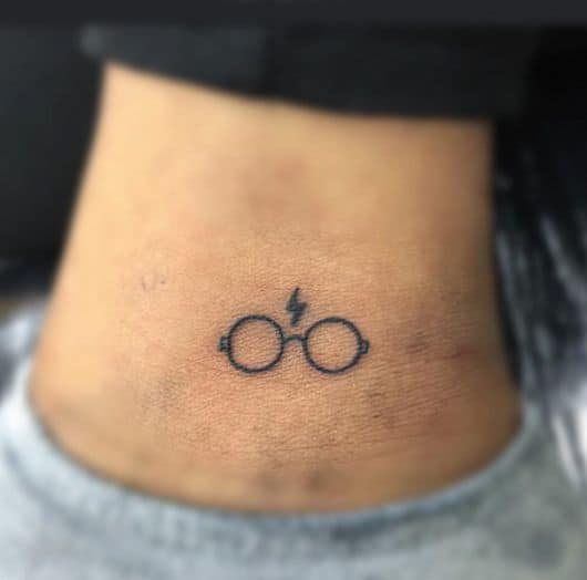 Tatuagem pequena de um óculos e cicatriz em homenagem ao personagem Harry Potter