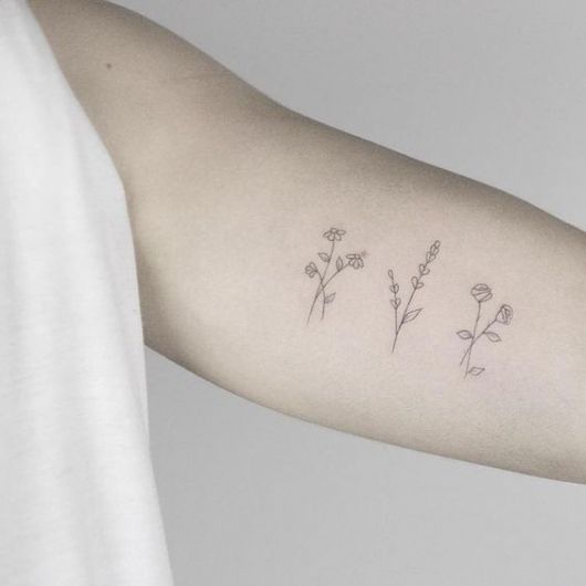 Três tatuagens de flores no braço