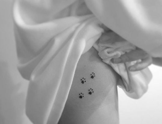 Tatuagem de patinhas de cachorro na costela