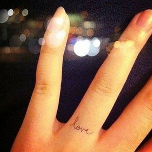 Tatuagem "love" no dedo anelar