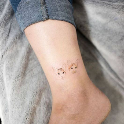 Tatuagem de duas cabeças de gato na perna
