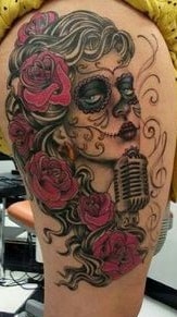 Tatuagem de uma mulher com flores na cabeça e um microfone vintage.