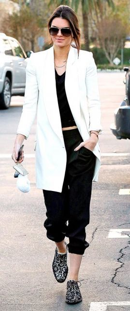 Kendal Jenner veste calça moletom preta, blusa no mesmo tom, sapato com brilhos.e blazer longo branco.