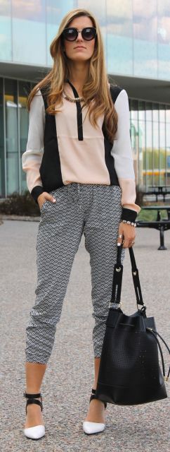 Modelo veste calça moletom cinza, blusa mesclada nas cores rosa, preto e branco e sapato com amarrações.