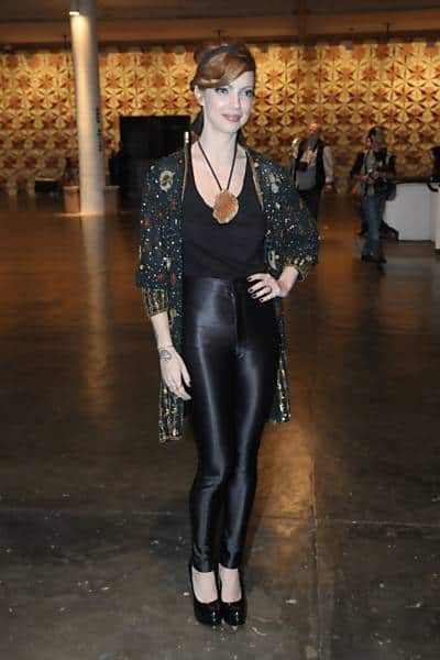 Julia Petit usa calça brilhosa, blusa preta e sobreposição, com colar estiloso.