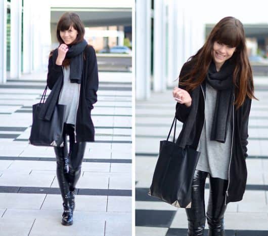 modelo usa casaco preto, blusa cinza, calça preta brilhosa e bolsa de couro.