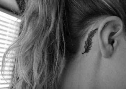 Modelo com tatuagem de pena, atras da orelha em foto preto e branco.