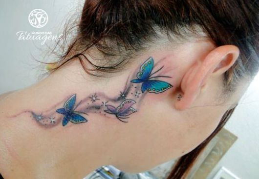 Tatuagem de três borboletas azuis, atrás da orelha.