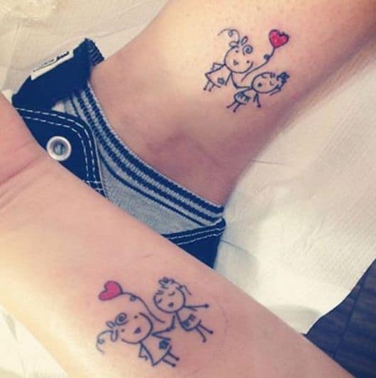 Modelo de tatuagem com duas bonequinhas e um coração.