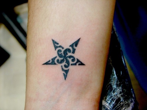 tatuagem de estrela no braço com uma estampa de flor dentro