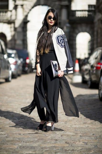 Modelo usa calça voal preta, sapato preto e jaqueta com manga em couro na cor branco e preto.