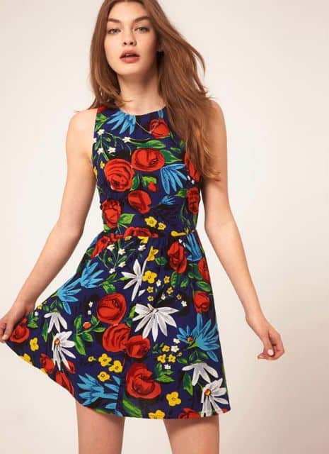 Modelo usa vestido floral, nos tons de preto,azul, branco, vermelho, amarelo.