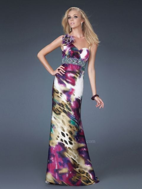 Modelo usa vestido reto com detalhe de flor no ombro, nas cores branco, roxo e verde.