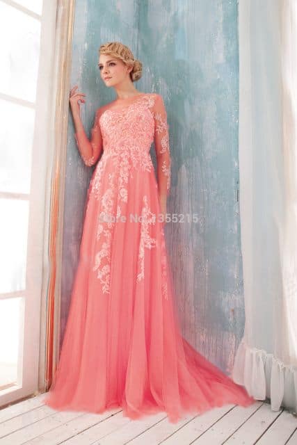 Modelo usa vestido rosa salmao com detalhes em renda.
