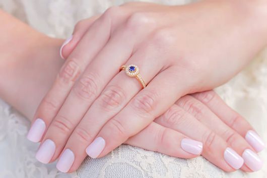 Modelo de anel de ouro com pedra pequena azul.