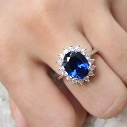 anel com brilhantes brancos, com pedra azul escuro.