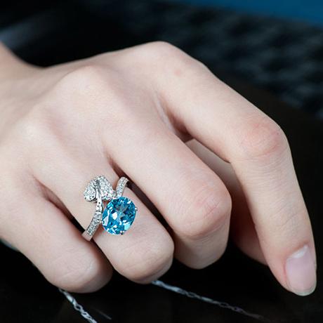 anel de prata com pedra azul clara com detalhes.
