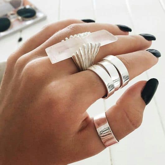 imagem mosta mão com anéis prata com pedra branca transparente.