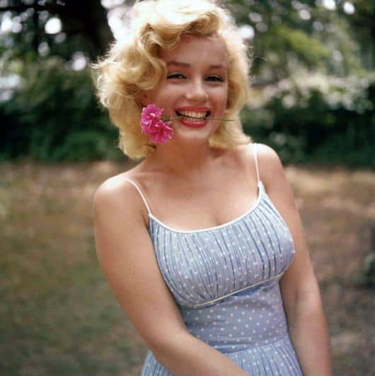 Marilyn Monroe usa blusa de alcinhas finas azul com estampada de bolinhas brancas.