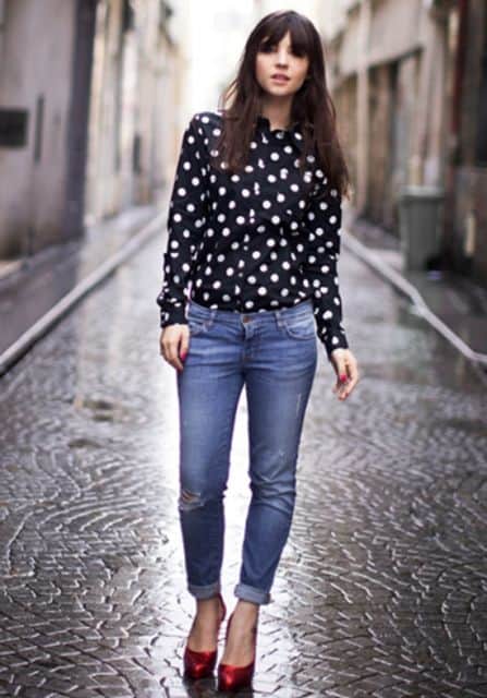 modelo usa calça jeans, sapato vermelho e blusa camisa preta de poá branco.