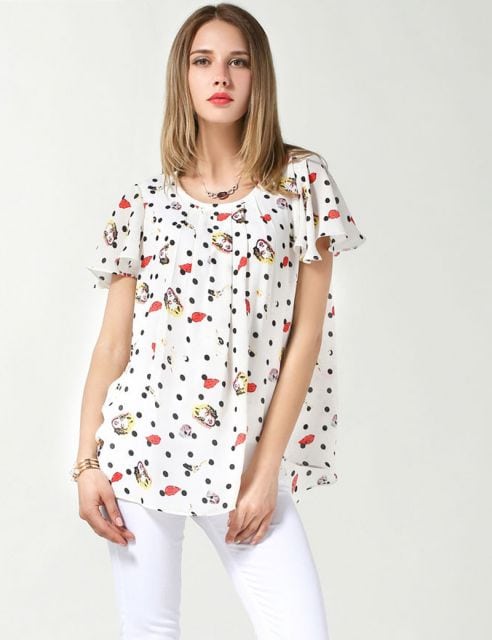 modelo usa blusa branca com bolinhas e estampas vermelhas.