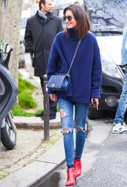 modelo usa calça jeans, blusao azul, bolsa no mesmo tom e bota vermelha.