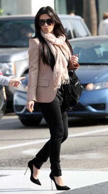 Kim Kadarshian usa blazer e lenço nude, calça , blusa e sapato preto.