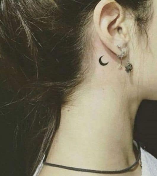 Tatuagem pequena de lua atras da orelha.