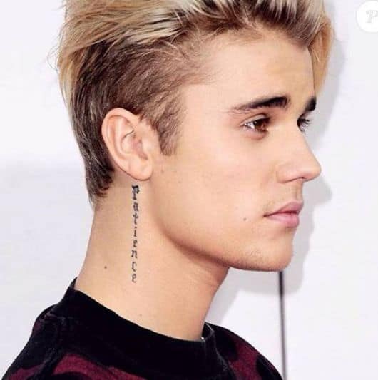 Justin Bieber com tatuagem atras da orelha paciencia.