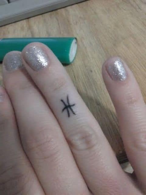 tatuagem do símbolo do signo de peixes no dedo