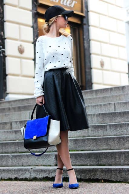 Modelo usa saia midi preta, blusa branca, boné feminino e sapatinho azul.