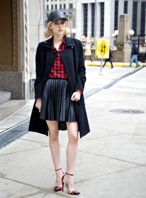 Modelo veste saia preta, casaco alongado, blusa vermelha e sapato preto.