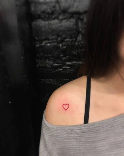 Tatuagem no ombro do contorno de uma coração em vermelho