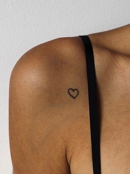Tatuagem do contorno de uma coração bem pequeno no ombro de uma mulher