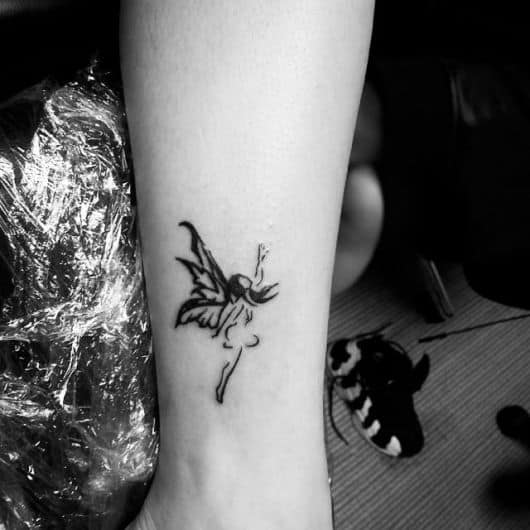 Tatuagem em preto e branco de uma fada olhando para cima com a mão estendida
