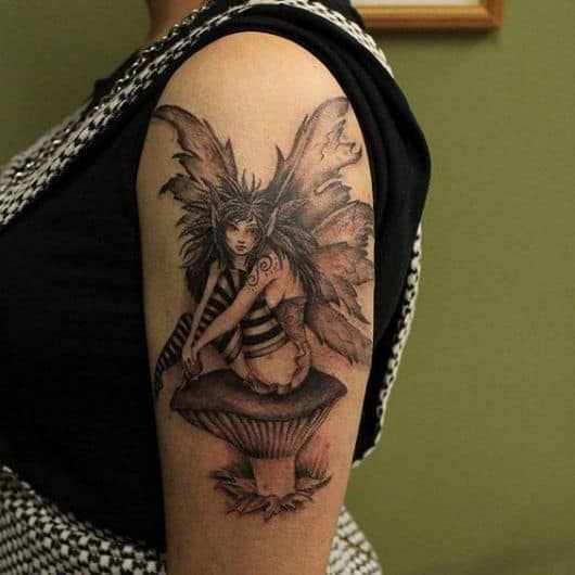 Tatuagem de fada no braço sentada em um cogumelo com as mãos na perna