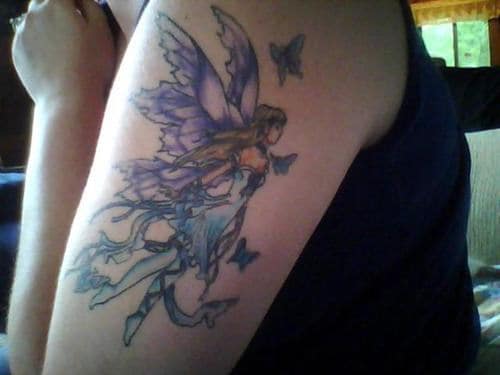 Tatuagem no braço de uma fada voando acompanhada por borboletas