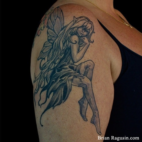 Tatuagem na parte superior do braço de uma fada com cabelos longos pintada em preto e branco