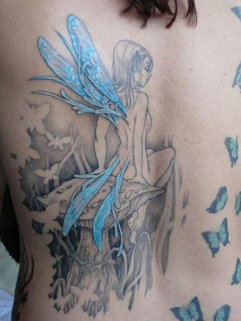 Tatuagem nas costas de uma fada sentada em um cogumelo com borboletas próximas a ela