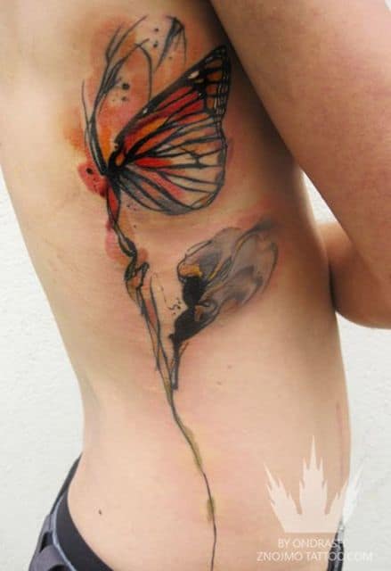 Tatuagem na costela com elementos abstratos de uma fada, pintada de vermelho e azul