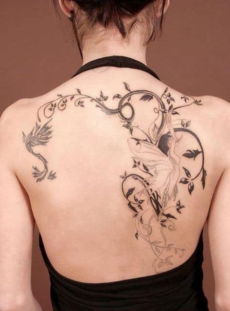 Tatuagem nas costas de uma mulher com uma fada pendurada em galhos de uma árvore que preenchem um bom espaço desta área do corpo