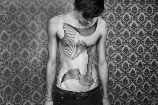Tatuagem geométrica de linhas tridimensionais que vão da barriga até o peito de um homem
