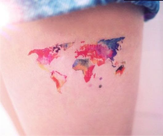 Tatuagem na parte superior da perna de uma mulher que reproduz o mapa mundi com cores saturadas