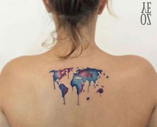Tatuagem nas costas de uma mulher com o mapa mundo pintado de roxo e azul e pequenos pingos escorrendo dos países
