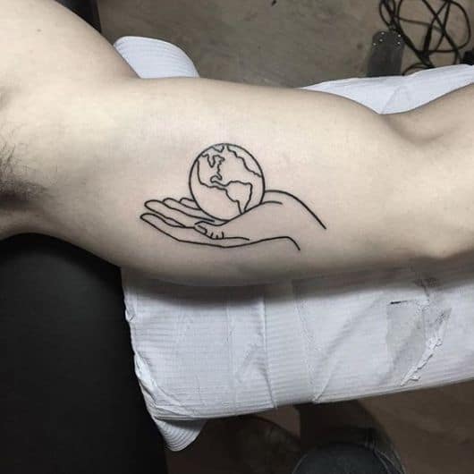 Tatuagem no braço de um homem de uma mão segurando o Globo Terrestre