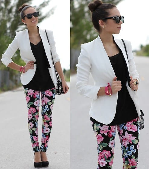 Modelo usa calça estampa floral rosa com preto, blazer branco, blusa preta e sapato preto.