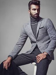 Modelo veste blazer cinza, blusa cinza gola alta e calça alfaiataria na mesma cor.