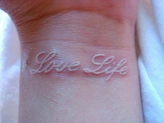 Tatuagem branca escrita love life ou "amor á vida"
