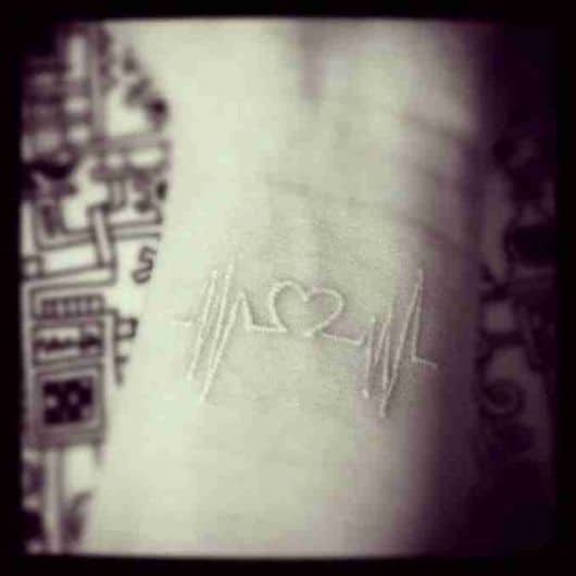 Tatuagem branca de linhas de batimento cardíaco com um coração no centro
